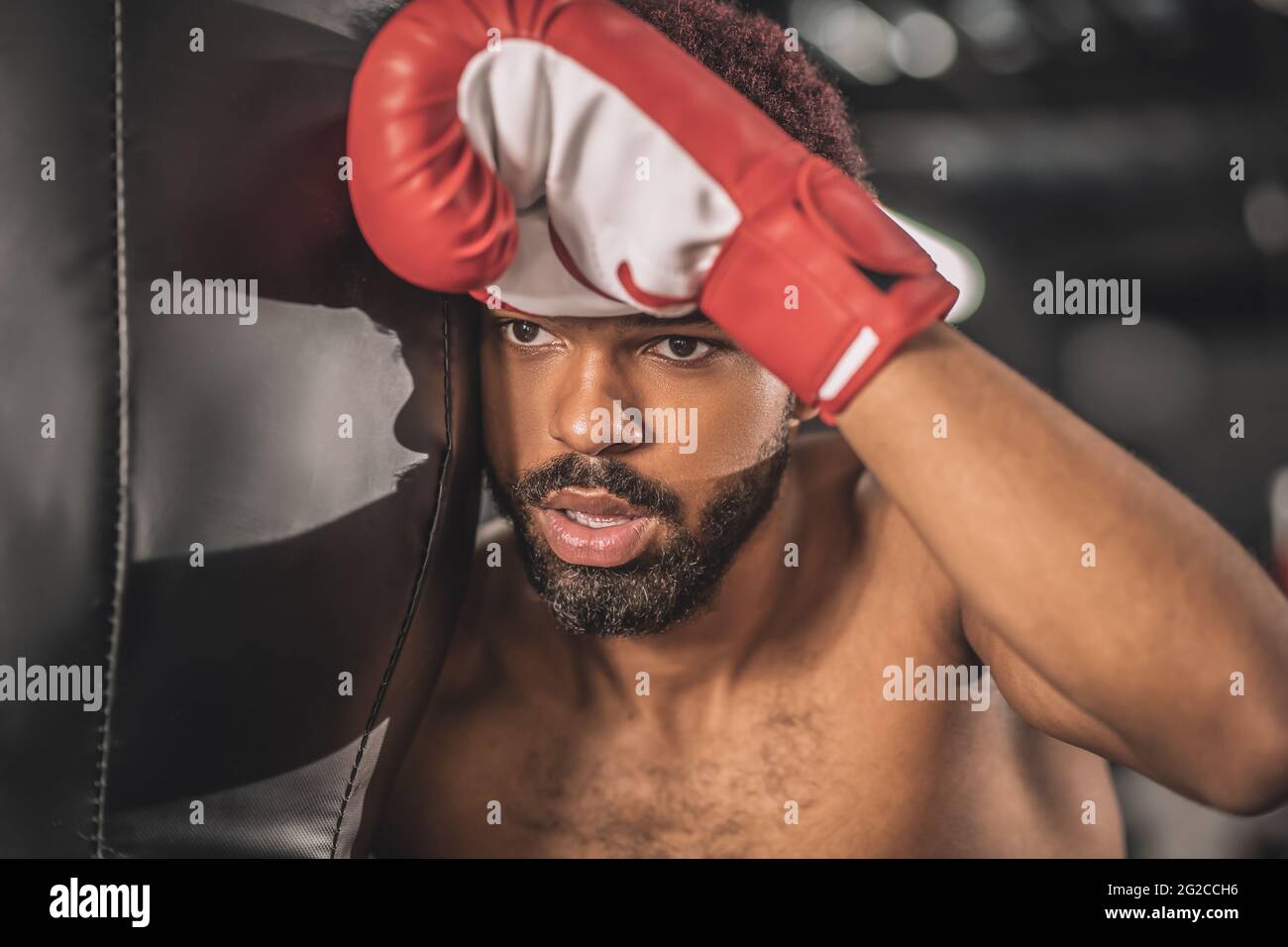 Junge dunkelhäutige Boxerin, die im Fitnessstudio trainiert und müde aussieht Stockfoto