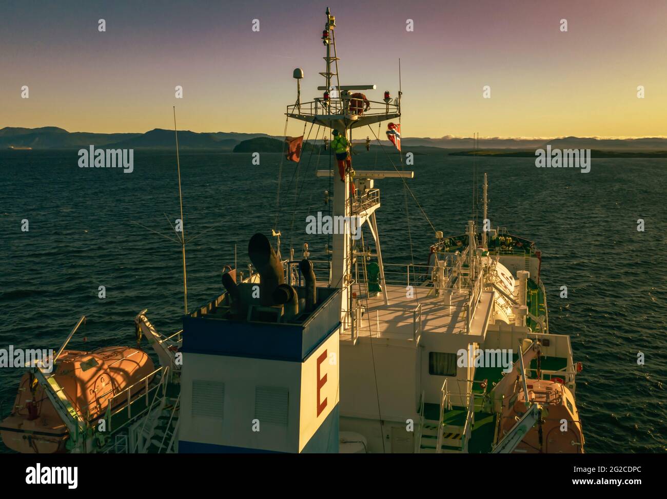 Seemann, der am Mast und am Gasträger an der Verankerung arbeitet. Drohnenaufnahmen und Tageslicht. Stockfoto