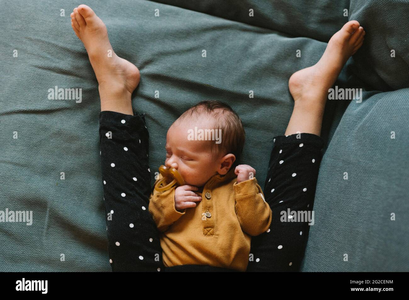 Aus dem hohen Winkel betrachtet, wie das Baby zwischen den Beinen des Geschwisterers schläft Stockfoto