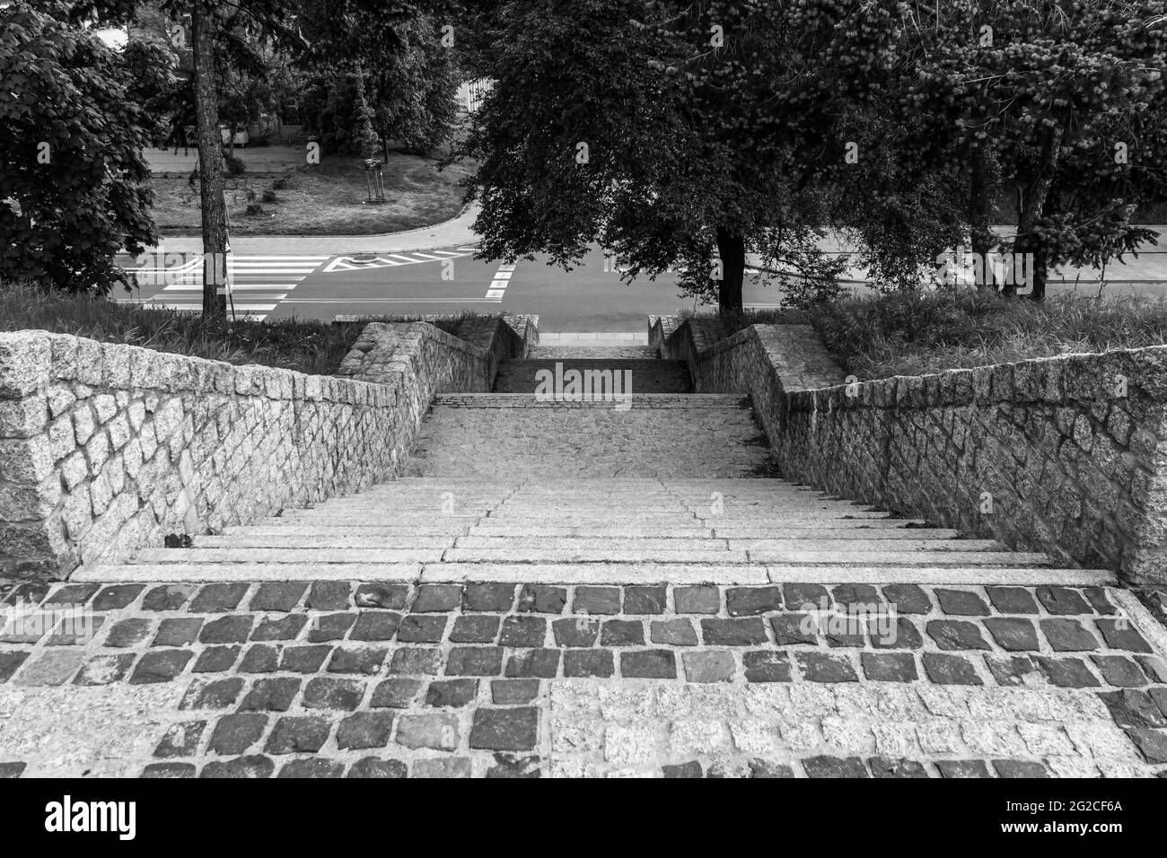Zaun und Treppe aus Granitsteinen. Ein gepflasterter Bereich mit einem Pflastersteinzaun. Aussichtsplattform im Stadtpark. Schwarzweiß-Foto Stockfoto