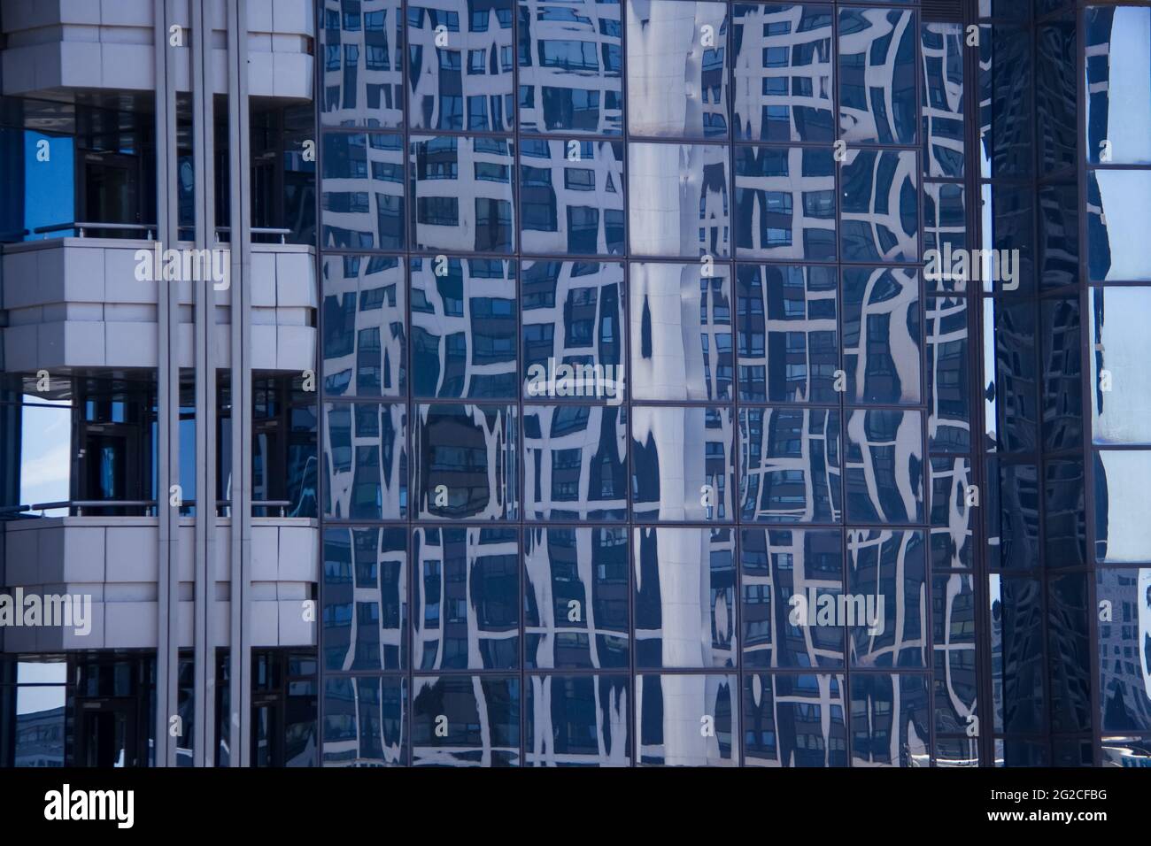 Spiegelung eines mehrstöckigen Gebäudes in der Glasfassade eines modernen Wolkenkratzers. Detail, Hintergrund Stockfoto