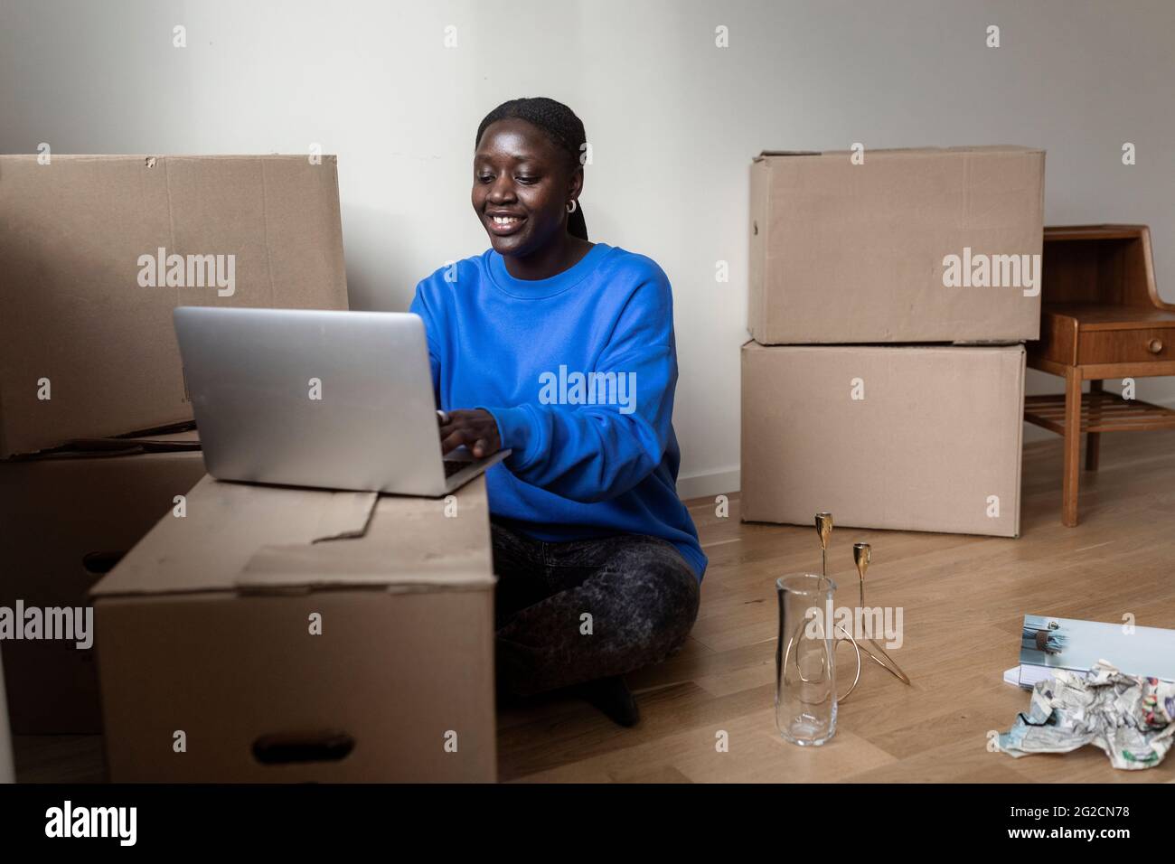 Frau mit Laptop, während sie zu Hause umzieht Stockfoto