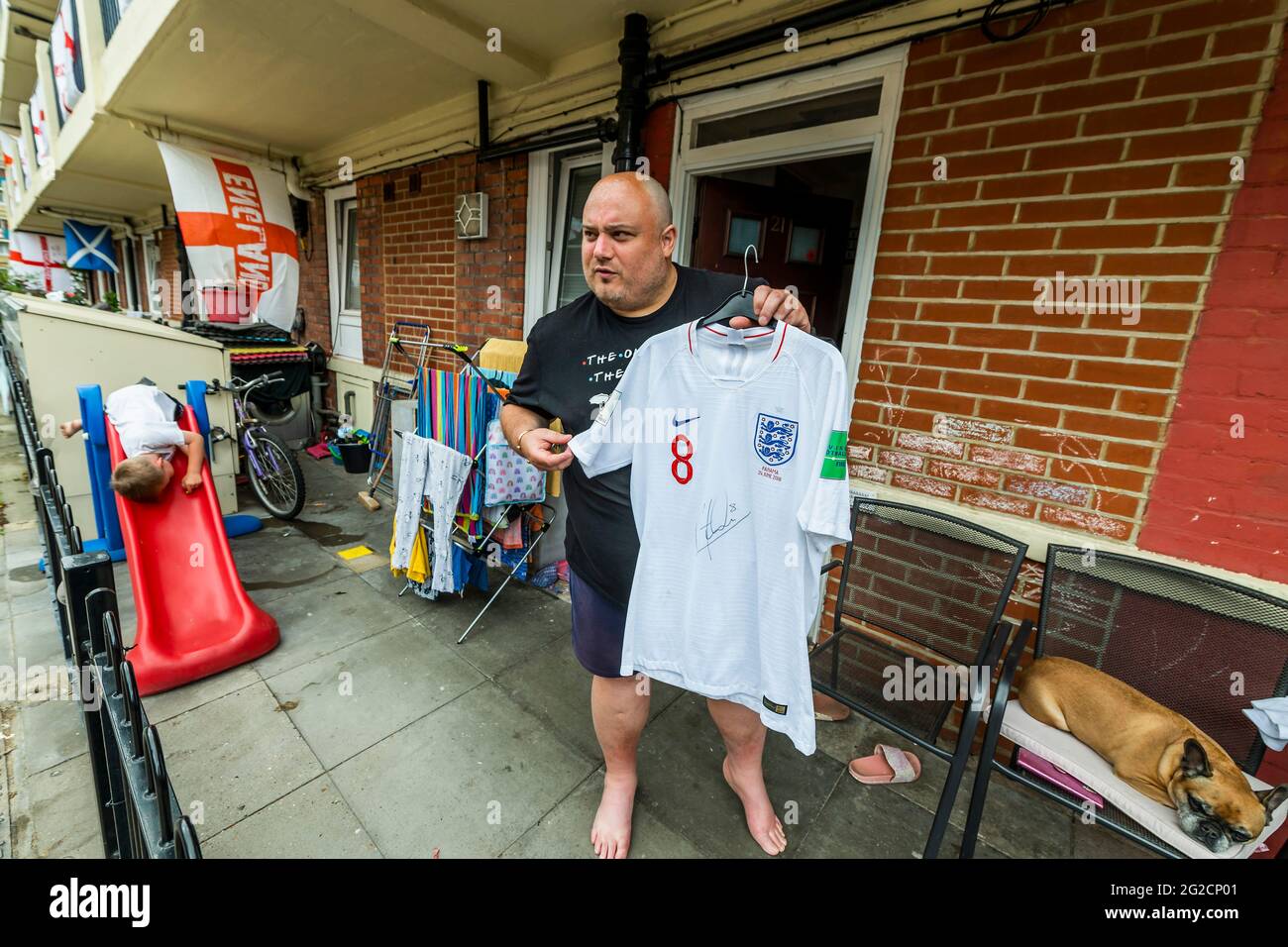 London, Großbritannien. Juni 2021. Chris Dowse, einer der Organisatoren, zeigt stolz sein handsigniertes England-Shirt vom Panama 2018 Turnier - Fußballbegeisterte Bewohner von Bermondseys Kirby Estate im Südosten Londons haben rund 400 England (Kreuz von St. George) Flaggen vor der Europameisterschaft, die an diesem Wochenende beginnt und in der Tat das Covid-verzögerte 2020 Turnier ist. Kredit: Guy Bell/Alamy Live Nachrichten Stockfoto