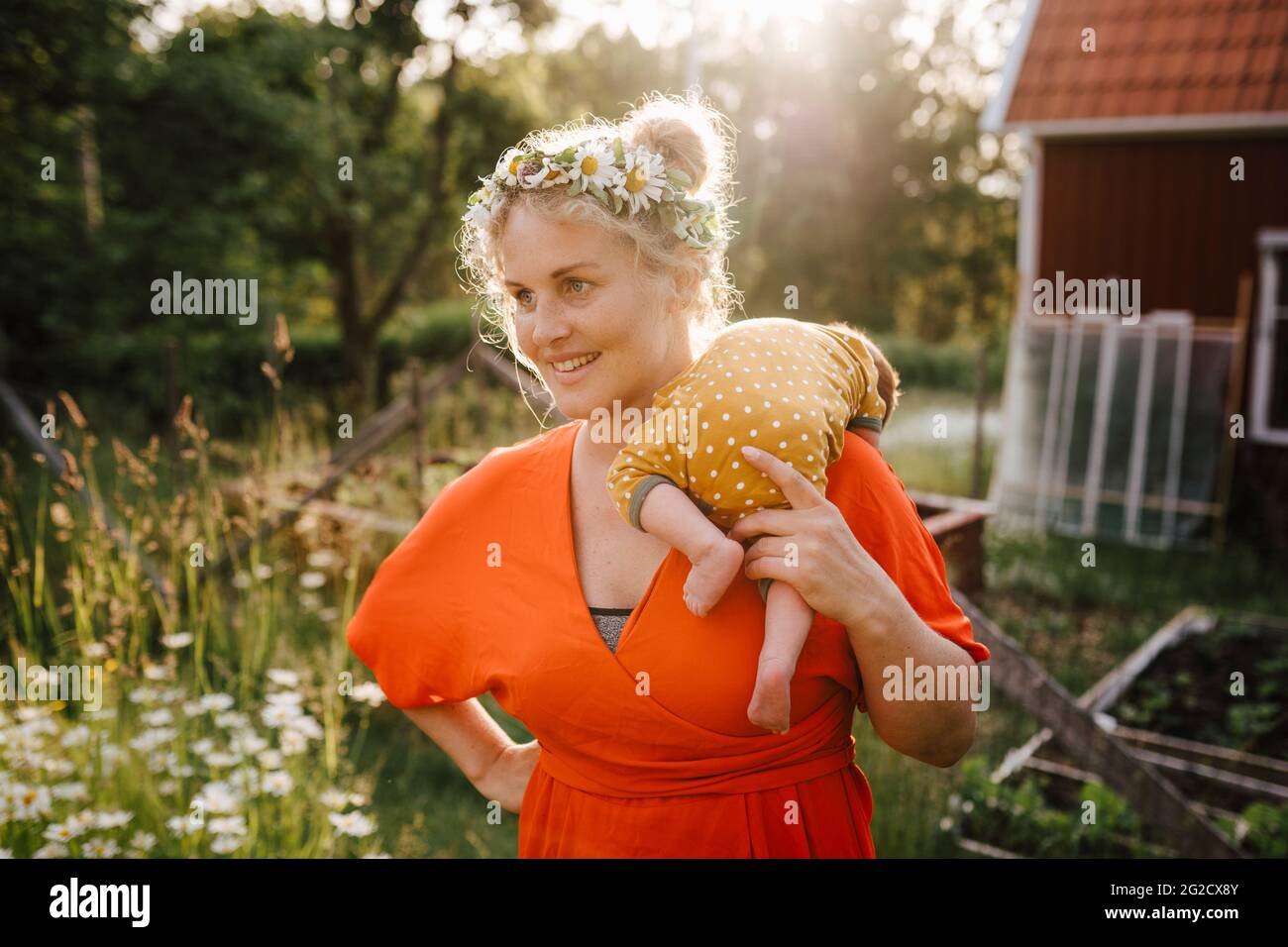 Lächelnde Frau, die das Baby auf der Schulter trägt Stockfoto