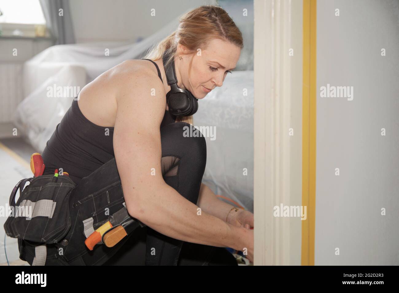 Frau mit Werkzeuggürtel, die zu Hause Reparaturen durchführt Stockfoto