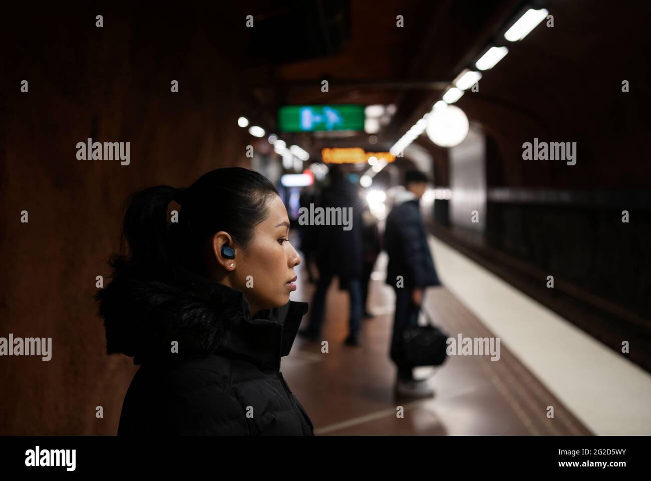 Frau mit Ohrhörern steht an der U-Bahn-Station Stockfoto