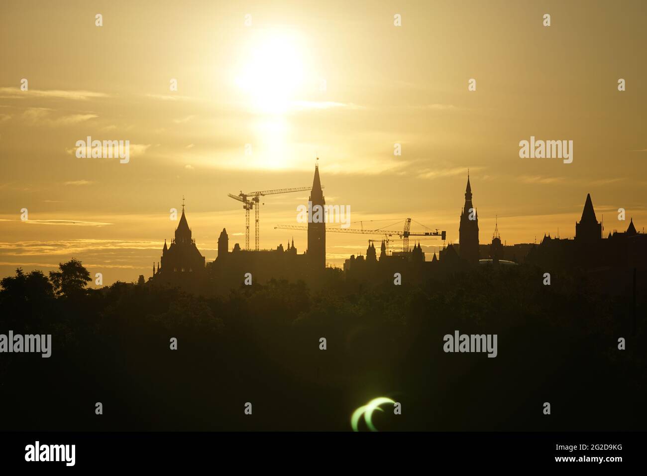 Ottawa, Kanada. 10. Juni 2021: Eine partielle Sonnenfinsternis wird am Donnerstag, 10. Juni 2021, über dem Parliament Hill in Ottawa, Kanada, gesehen. Die ringförmige oder „Feuerring“-Sonnenfinsternis ist nur für einige Menschen in Grönland, Nordrussland und Kanada sichtbar. In Kanadas National Capital Region lag die Sonne am Höhepunkt der Sonnenfinsternis weniger als 3 Grad über dem Horizont, sichtbar nur als schmale Sichel mit den landschaftlich reizvollen Regierungsgebäuden des Landes, die einen dramatischen Hintergrund bieten. Quelle: George Ross/Alamy Live News Stockfoto