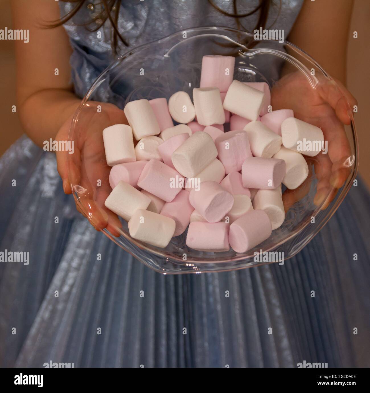 Foto von einem kleinen Mädchen mit blauem Kleid bietet bunte Süßigkeiten für zu Hause begrüßen in das Fest, Süßigkeiten an den Hausgast als Kompliment zu geben Stockfoto