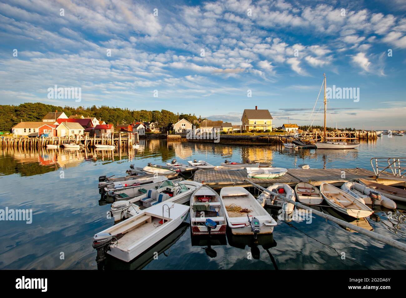 Skiffs am Dock mit Friendship Sloop im Hintergrund, Carvers Harbour, Vinalhaven Island, Maine, USA Stockfoto