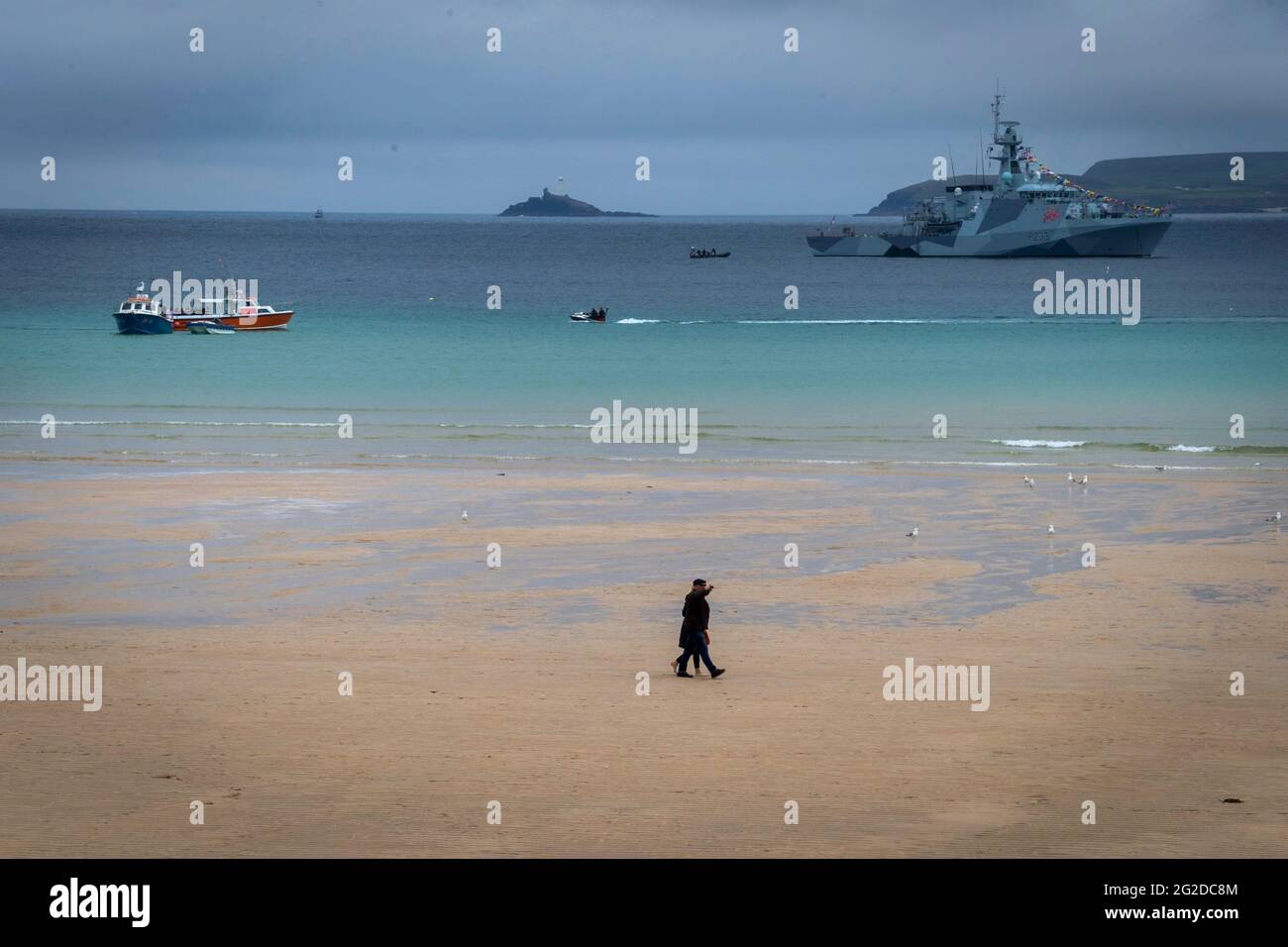 St Ives, Großbritannien. Juni 2021. Touristen genießen den Strand unter dem Schatten eines Marinekriegs, das während des G7-Gipfels vor der Küste von St. Ives angedockt ist.der 47. G7-Gipfel wird in Cornwall im Südwesten Englands ausgerichtet. (Foto von Andy Barton/SOPA Images/Sipa USA) Quelle: SIPA USA/Alamy Live News Stockfoto