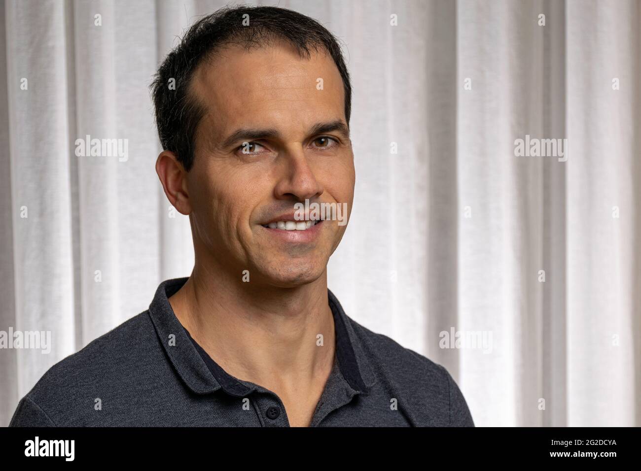 Reifer Mann (44 Jahre alt) in Fotosession mit dunkelblauem Poloshirt und macht mehrere Gesichter. Stockfoto