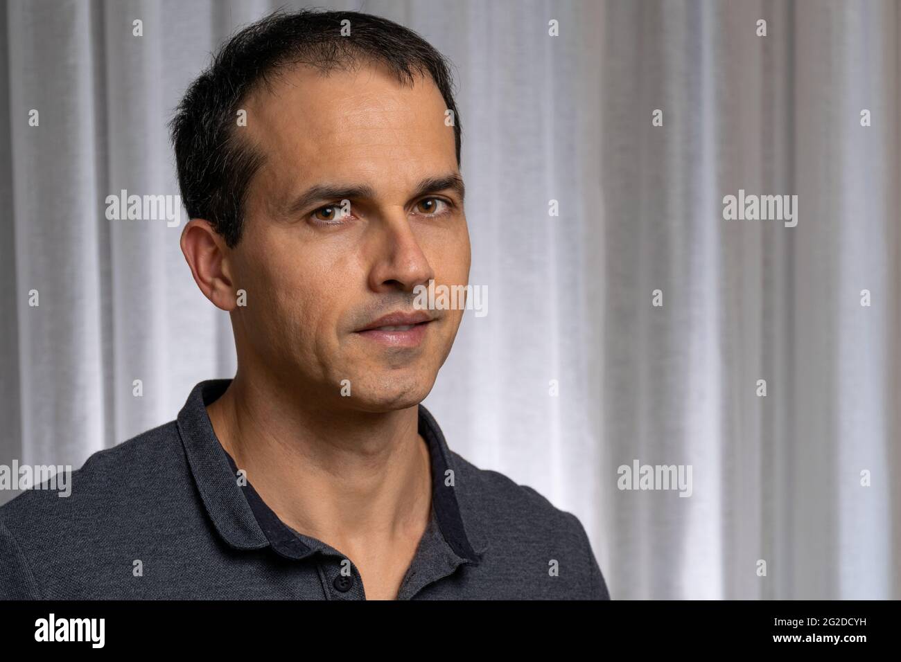 Reifer Mann (44 Jahre alt) in Fotosession mit dunkelblauem Poloshirt und macht mehrere Gesichter. Stockfoto