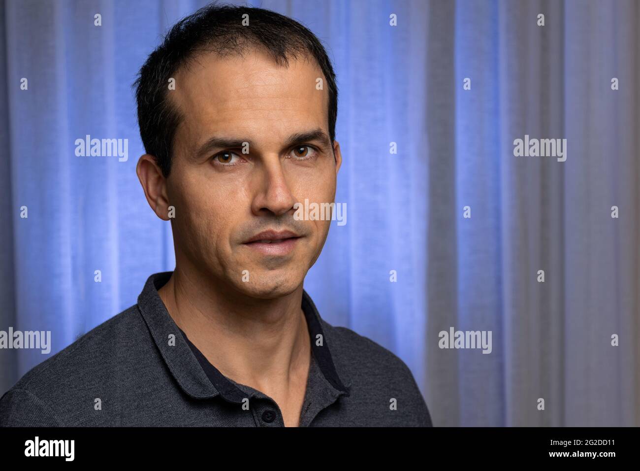 Reifer Mann (44 Jahre alt) in Fotosession mit dunkelblauem Poloshirt und macht mehrere Gesichter. Stockfoto