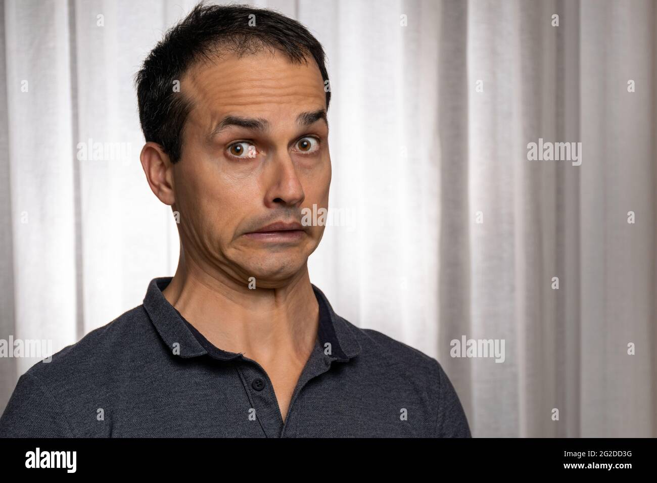 Reifer Mann (44 Jahre alt) in Fotosession mit dunkelblauem Poloshirt und macht mehrere Gesichter. Stockfoto