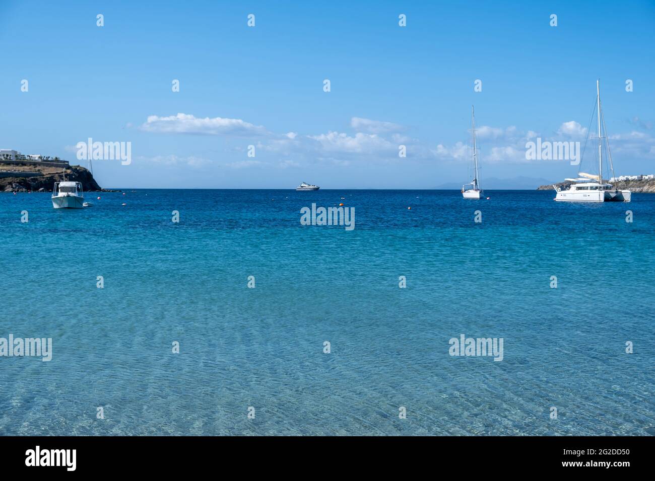 Mykonos Island, Kykladen. Griechenland. Ornos Sandstrand, Sommerurlaub Konzept. Segelboote und Yachten liegen auf offenem Meer, blauer Himmel im Hintergrund. Segeln Stockfoto