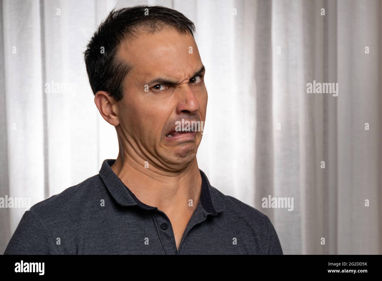 Reifer Mann (44 Jahre alt) in Fotosession mit dunkelblauem Poloshirt und macht mehrere Gesichter. Stockfoto