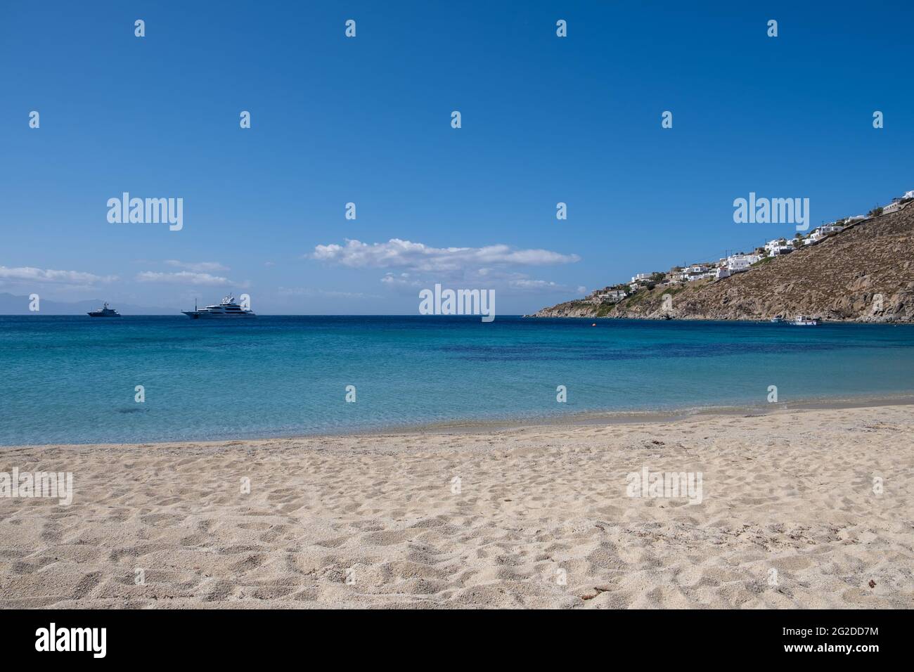 Mykonos Island, Kykladen. Griechenland. Kreuzfahrt an der Ägäis. Psarou Sandstrand, Sommerferien Konzept. Die Yachten liegen auf offenem Meer, der Himmel ist klar und blau Stockfoto