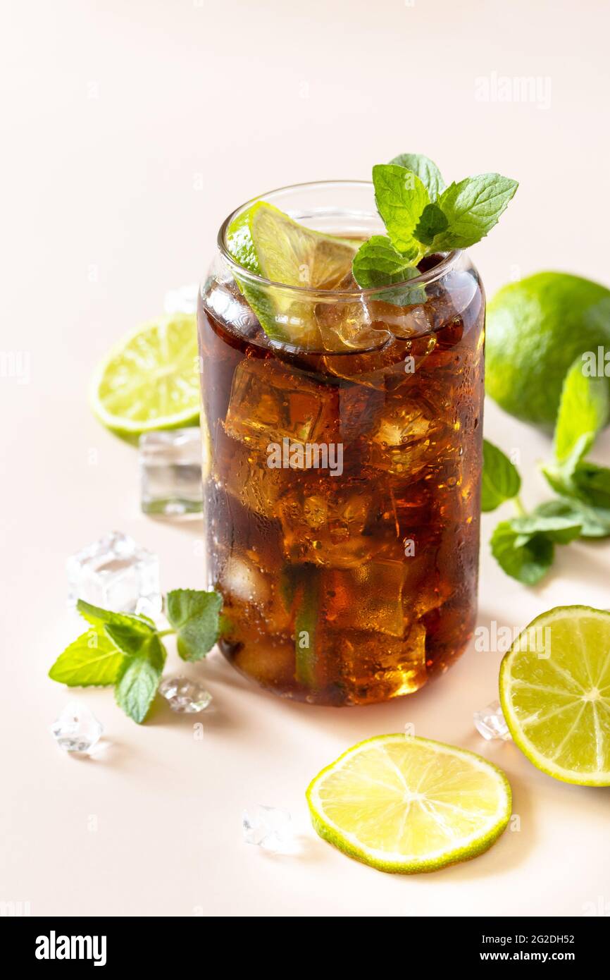 Cuba Libre alkoholisches Getränk, Cola mit Eiswürfeln oder Limonade auf pastellbraunem Hintergrund. Stockfoto