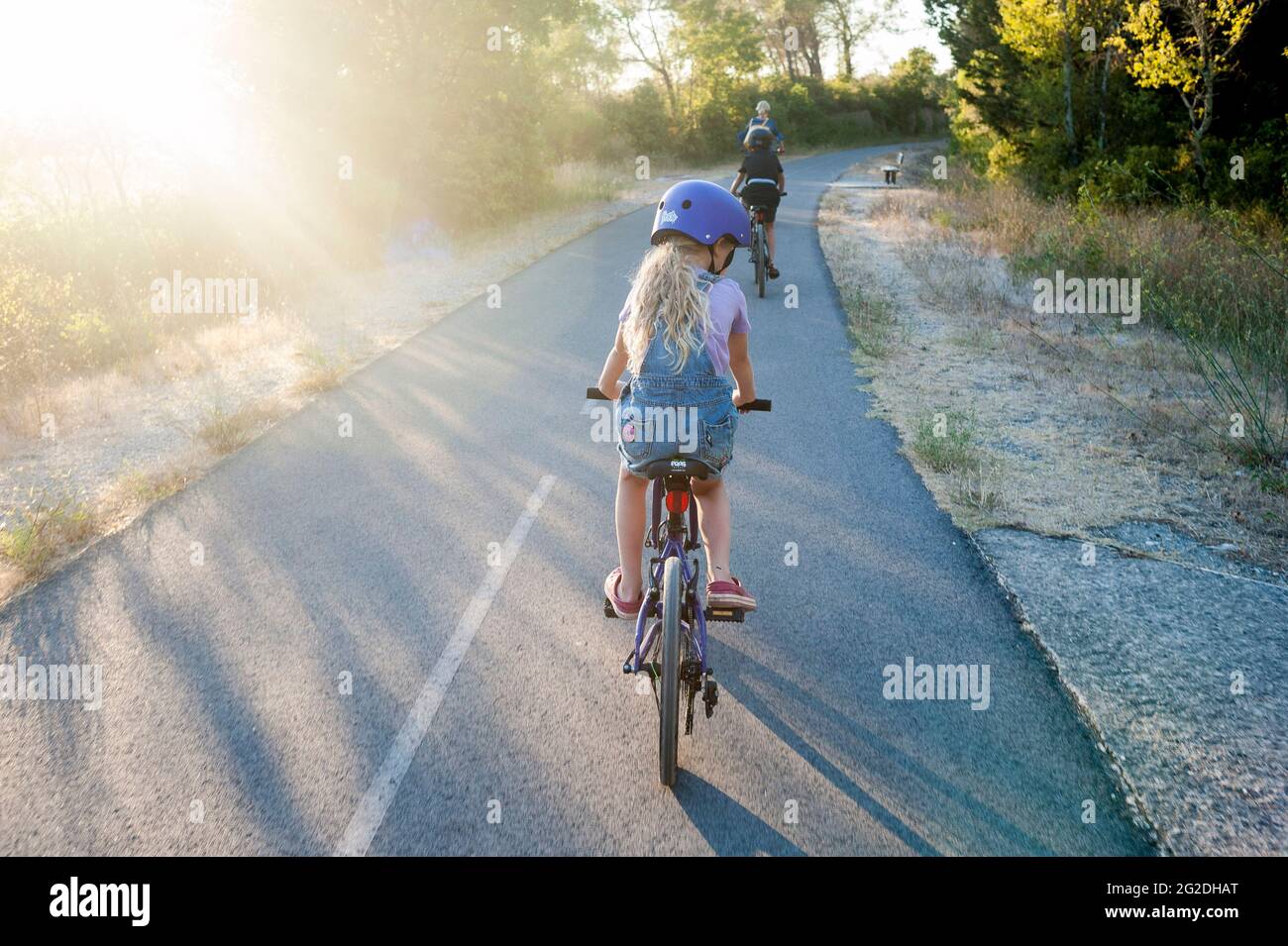 Ein Kind auf einem Kinderfahrrad auf einem Radweg mit Helm. Stockfoto