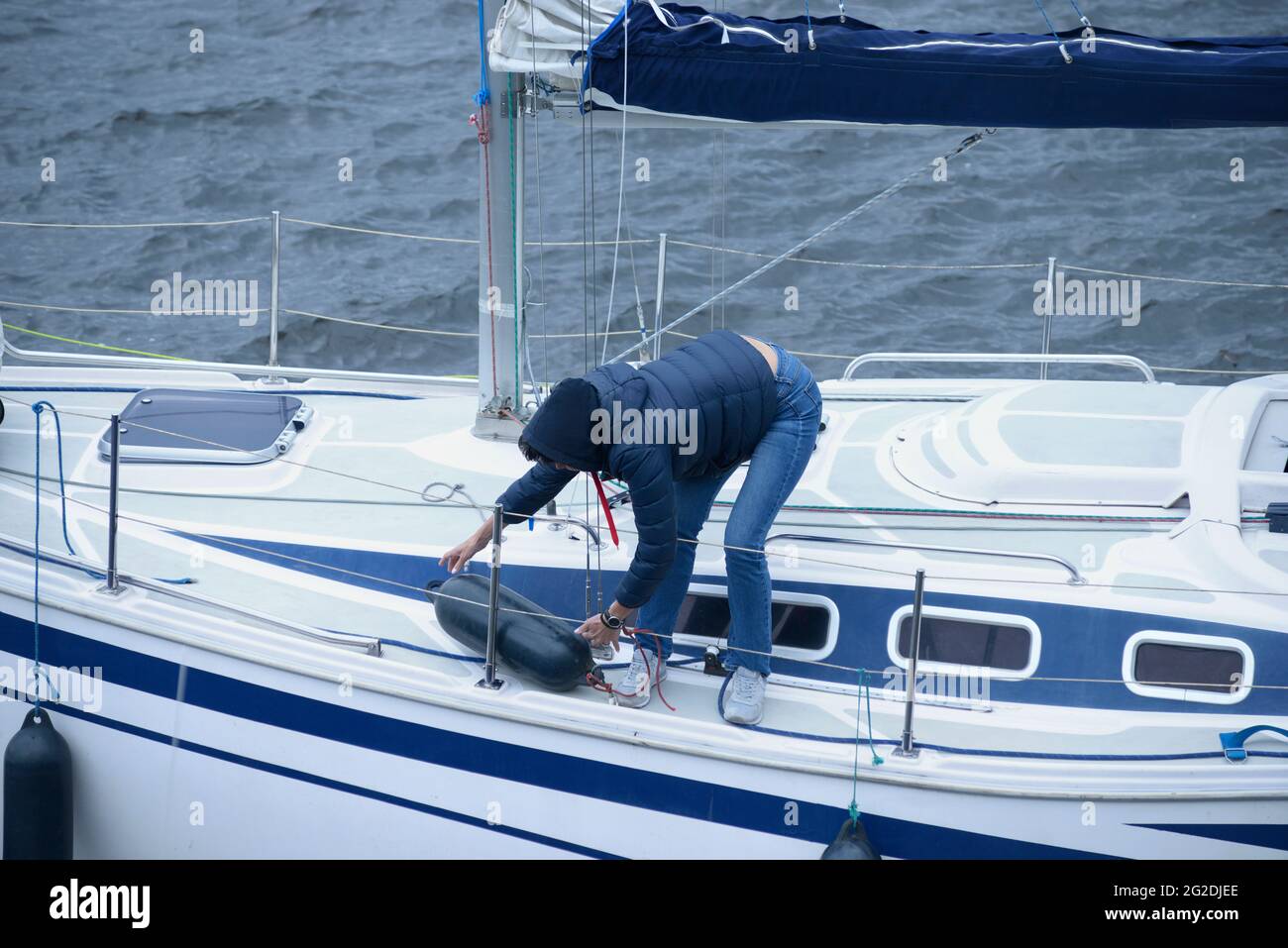 Der Segler steht auf einem Deck einer Segelyacht und legt die Kotflügel über Bord, um an einem Liegeplatz festzumachen. Amateur-Regatta, die dem Tag der Stadt gewidmet ist. 30.Mai 202 Stockfoto