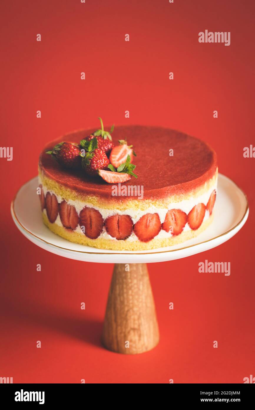 Französischer Erdbeerkuchen Fraisier auf Kuchenständer auf rotem Hintergrund. Stockfoto