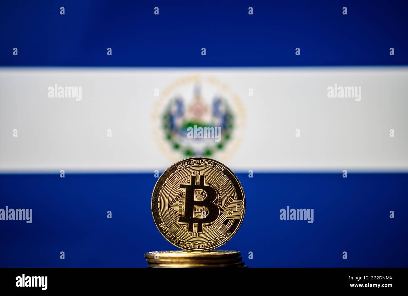 Bitcoin-Münze vor der verschwommenen Nationalflagge von Salvador. El Salvador ist das erste Land, das Bitcoin als gesetzliches Zahlungsmittel annimmt. Co Stockfoto