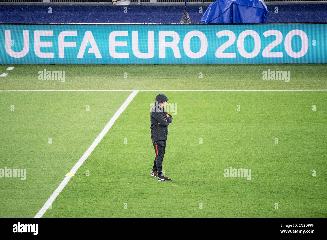 Rom, Italien. Juni 2021. Fußball: Europameisterschaft, türkische Nationalmannschaft, Training im Olympiastadion in Rom. Trainer Senol Günes aus der Türkei beobachtet das Training mit seiner im Regen tief ins Gesicht gezogenen Kapuze. Im Hintergrund sieht man die Worte „UEFA EURO 2020“ auf einer digitalen Tafel. Quelle: Matthias Balk/dpa/Alamy Live News Stockfoto