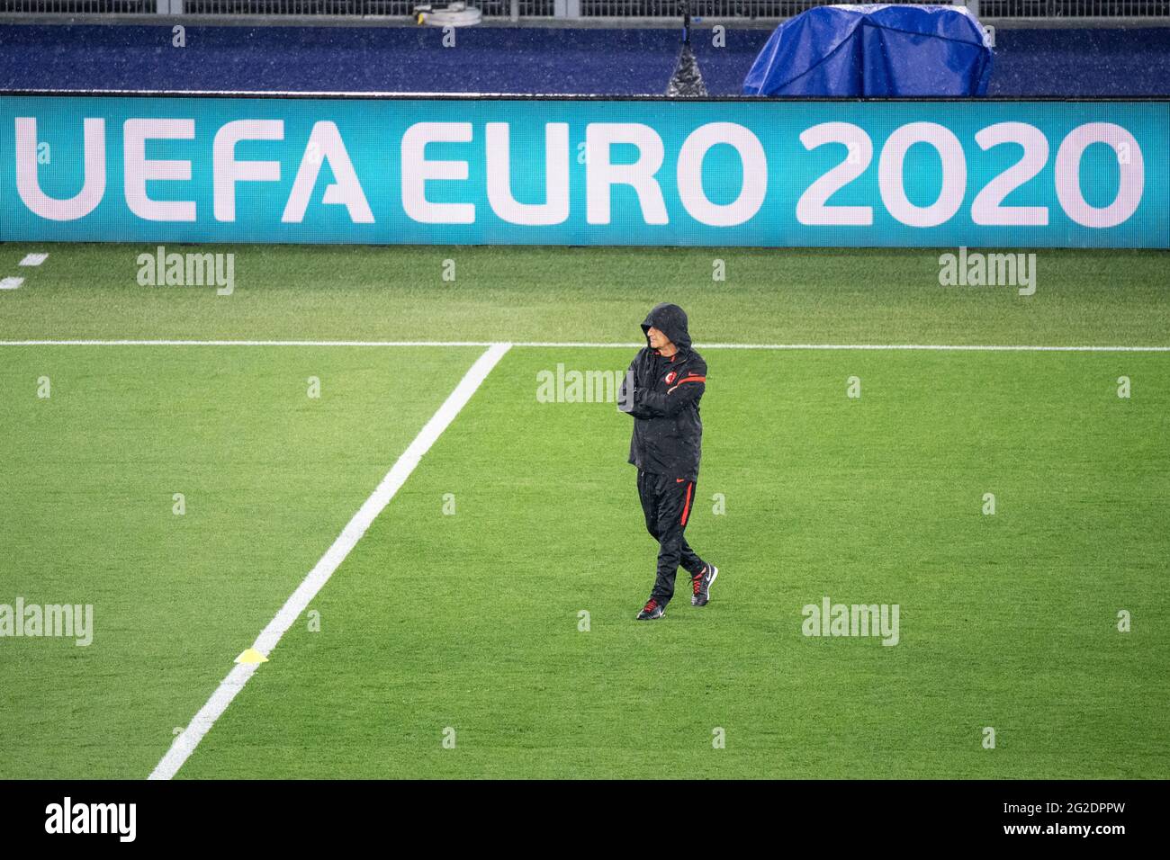 Rom, Italien. Juni 2021. Fußball: Europameisterschaft, türkische Nationalmannschaft, Training im Olympiastadion in Rom. Trainer Senol Günes aus der Türkei beobachtet das Training mit seiner im Regen tief ins Gesicht gezogenen Kapuze. Im Hintergrund sieht man die Worte „UEFA EURO 2020“ auf einer digitalen Tafel. Quelle: Matthias Balk/dpa/Alamy Live News Stockfoto