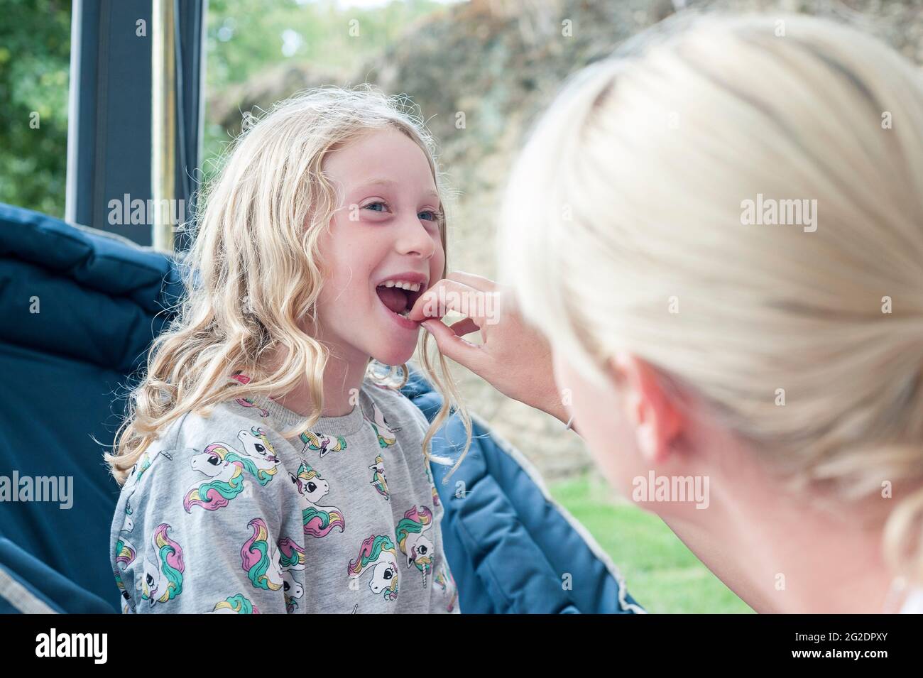 Ein junges Mädchen hat ihren ersten Zahn von ihrer Mutter herausgezogen. Stockfoto