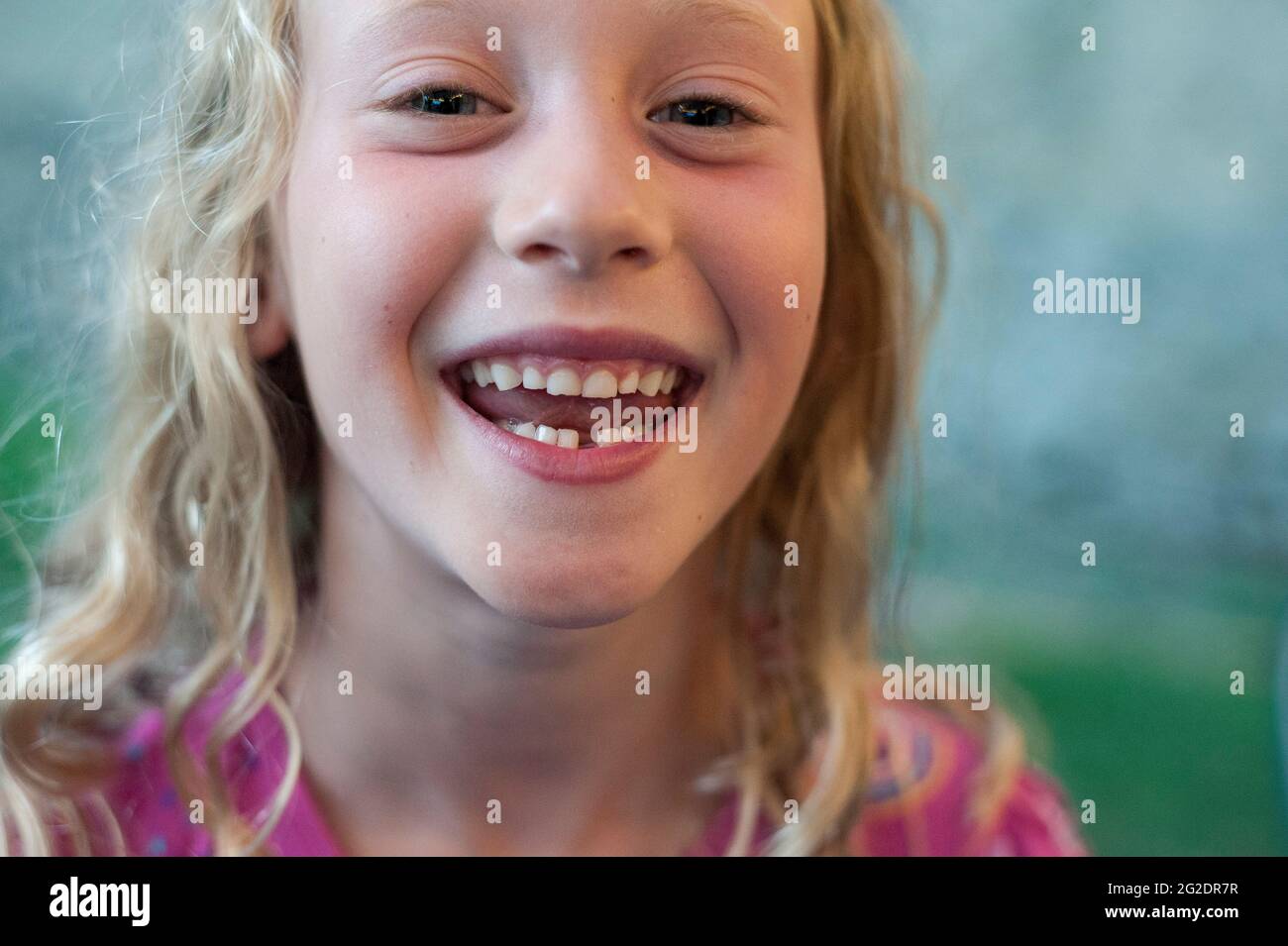 Ein junges Mädchen zeigt stolz ihren Mund und die Lücke in ihren Zähnen, wo ihr erster Zahn herausfiel. Stockfoto