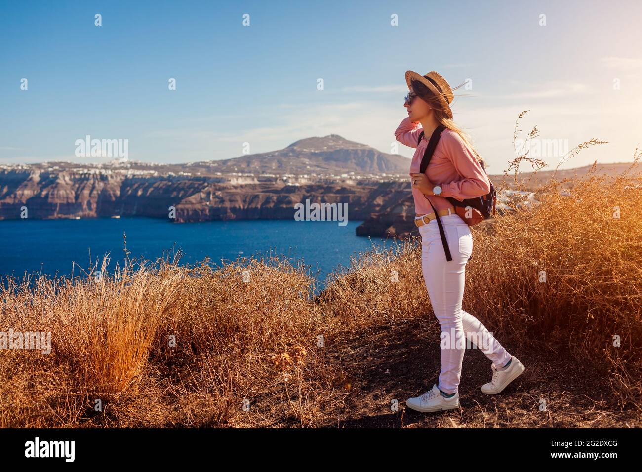 Reisende Frau, die auf Santorini, Griechenland, die Landschaft genießen. Glückliches Mädchen mit Rucksack genießt am Meer Caldera Blick. Tourismus Stockfoto