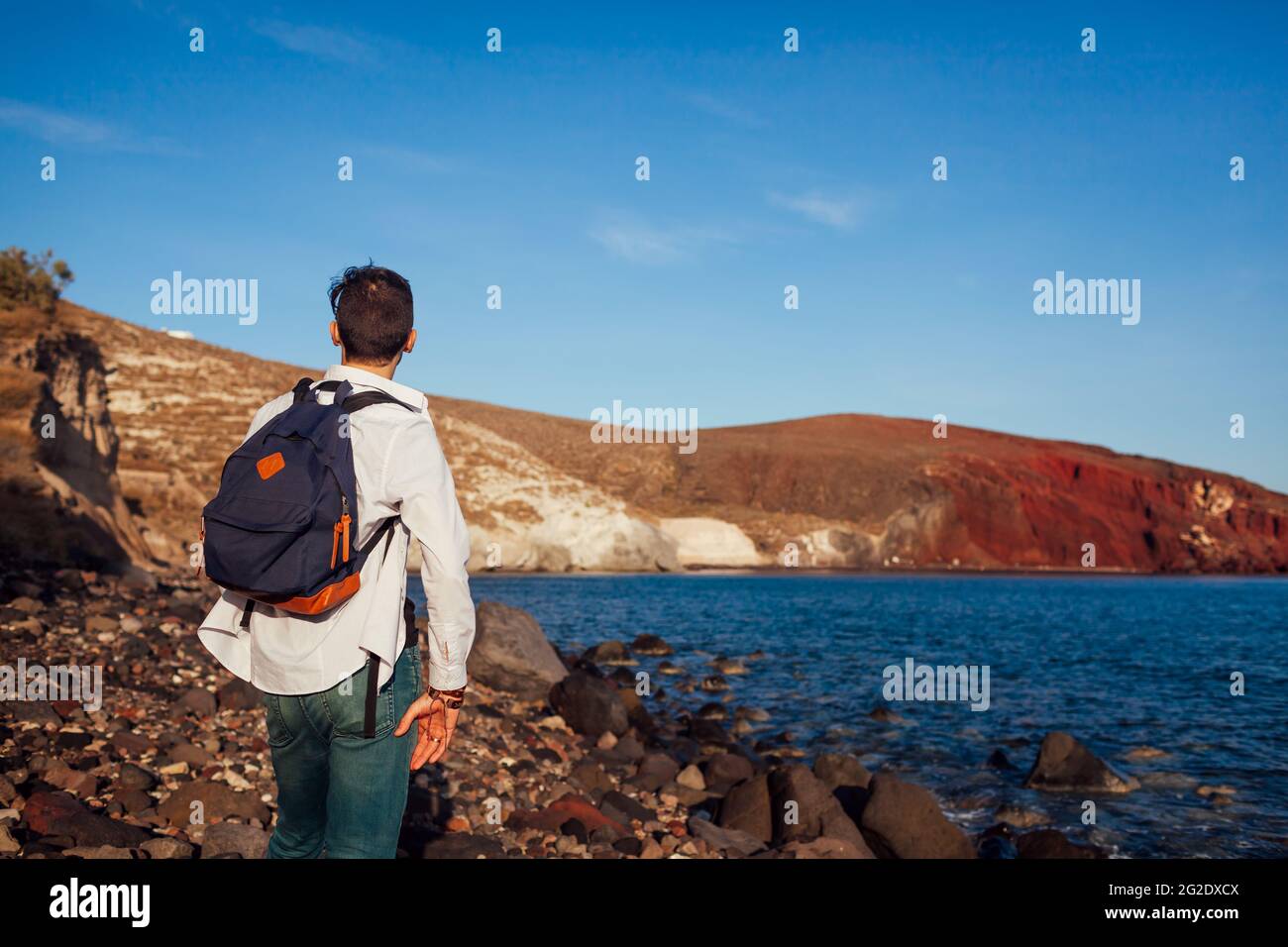 Reisende, die die rote Strandlandschaft in Akrotiri, Santorini, Griechenland, betrachten und den Blick auf das Meer und die Berge bewundern. Reisen. Sommerurlaub Stockfoto Reisende, die die rote Strandlandschaft in Akrotiri, Santorini, Griechenland, betrachten und den Blick auf das Meer und die Berge bewundern. Reisen. Sommerurlaub Stockfoto