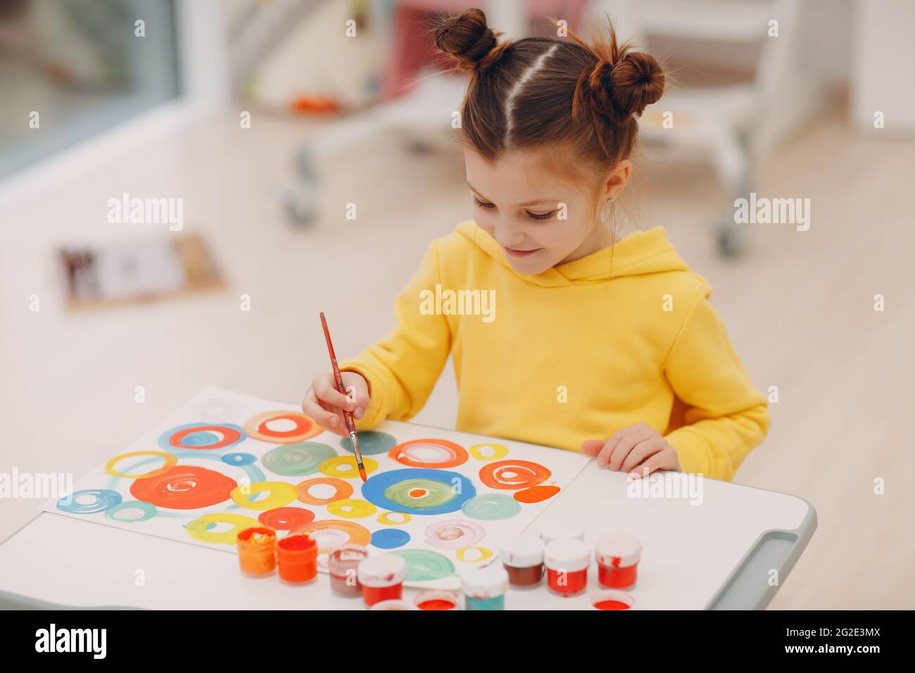 Kleines Mädchen Malerei Kunst Bild indoor Kindergarten. Home Tisch mit Pinsel und Aquarellfarben Stockfoto