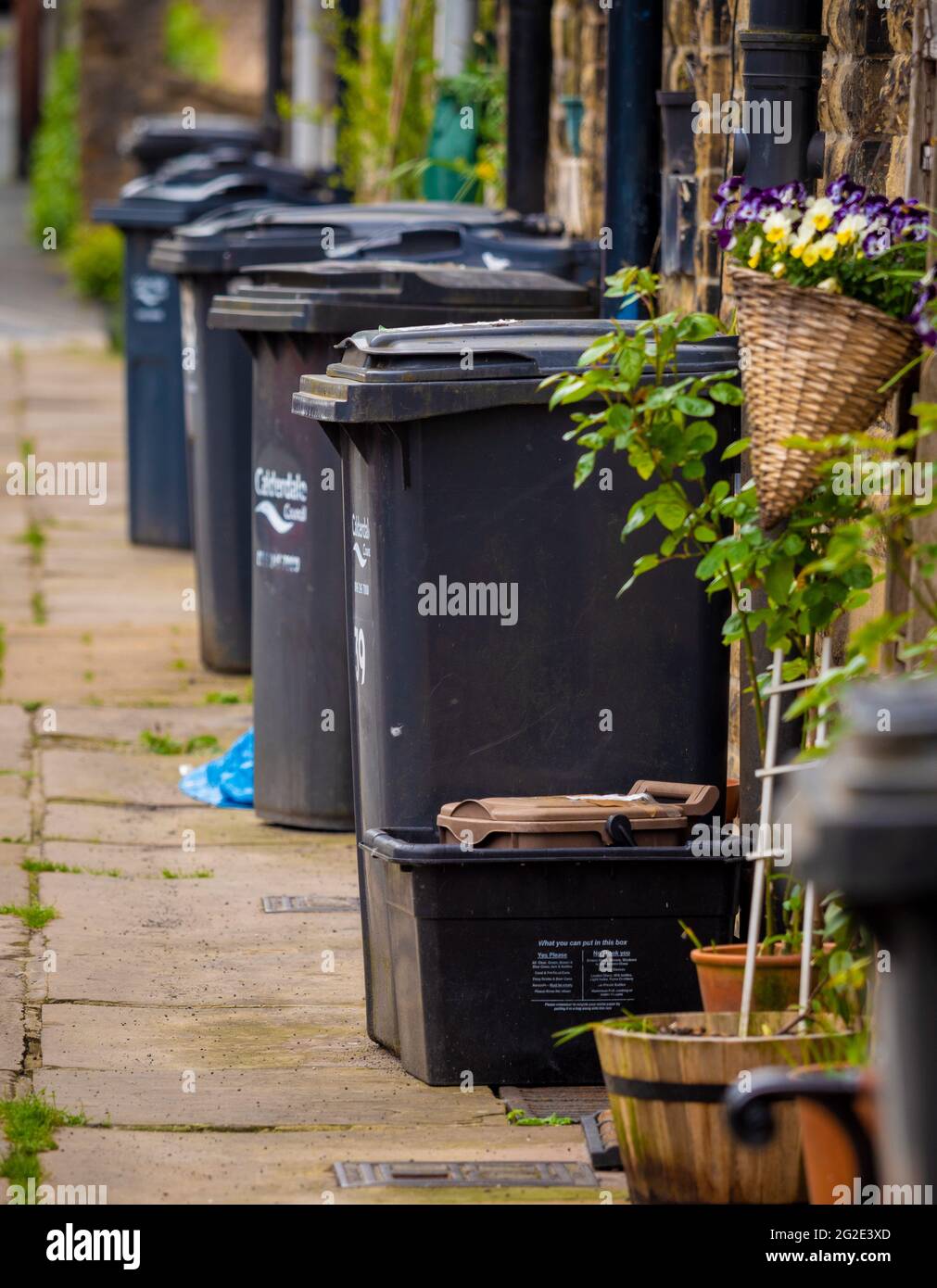 Vor den Häusern in West Yorkshire, Hebden Bridge, Großbritannien, standen Wheely Mülltonnen Stockfoto