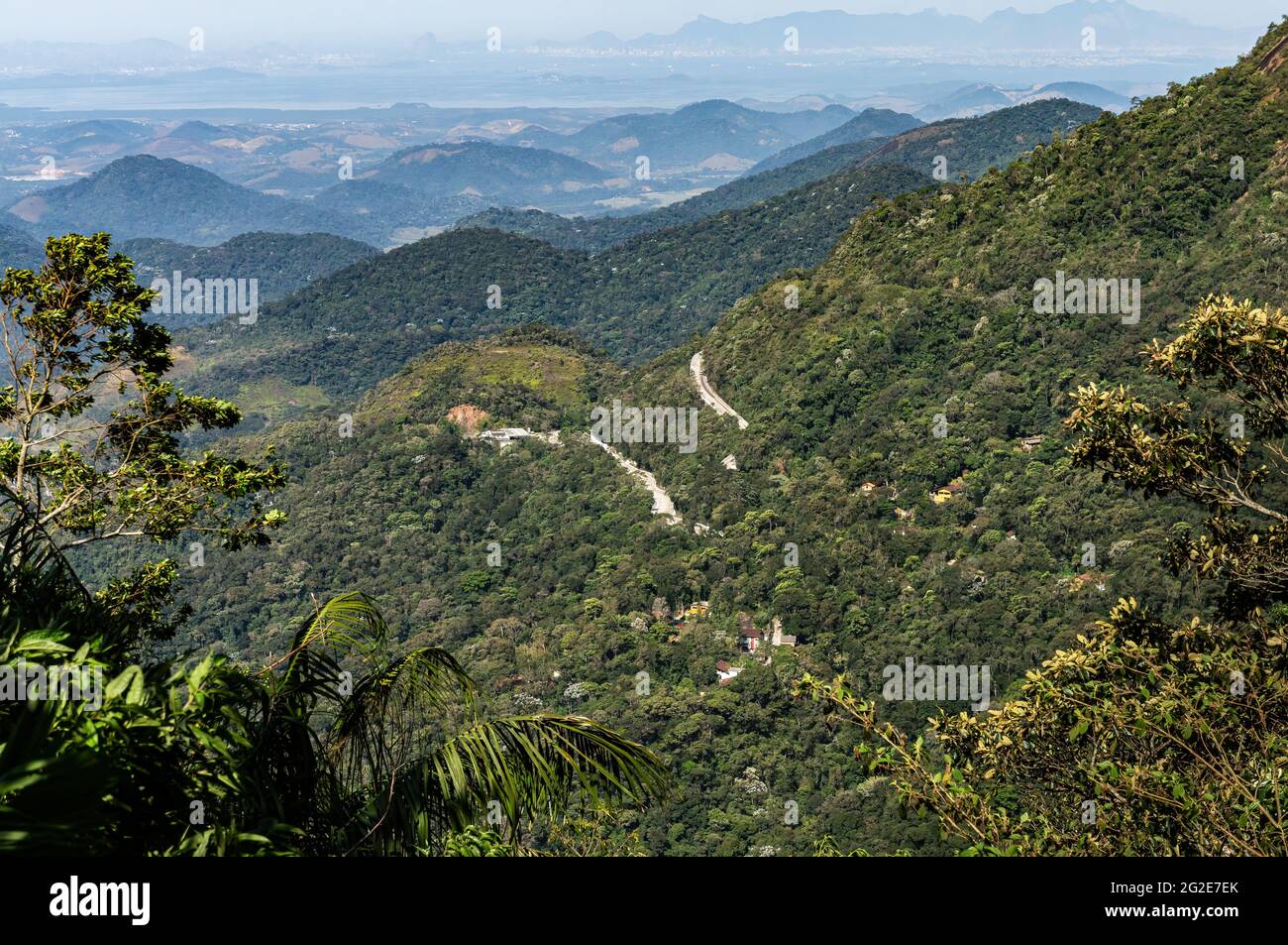 Blick vom Mirante do Soberbo Aussichtspunkt auf den kurvenreichen Rio-Teresopolis Highway, der durch die dichte grüne Vegetation der Organ Range Berge führt. Stockfoto