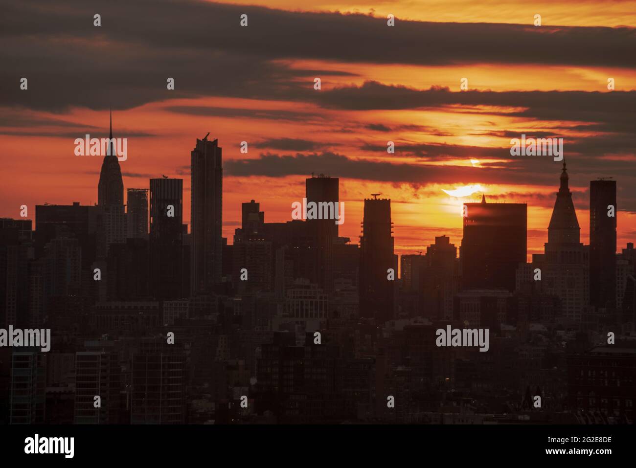 10. Juni 2021 partielle Sonnenfinsternis über der Skyline von NYC bei Sonnenaufgang Stockfoto