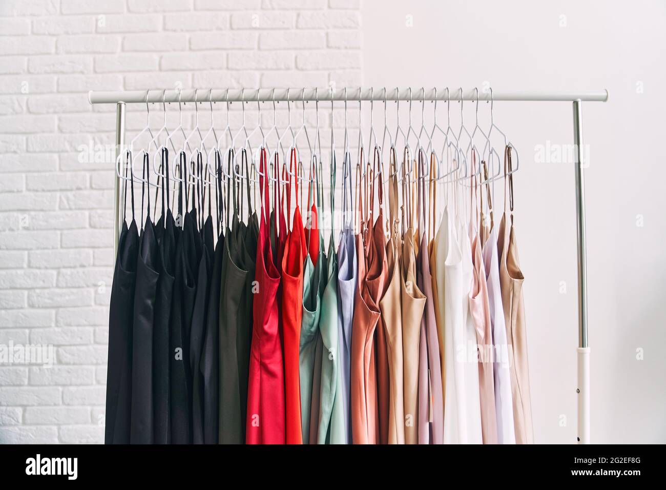 Bunte Kleider hängen an Kleiderbügeln im Laden. Verkauf von Frauenkleider Stockfoto