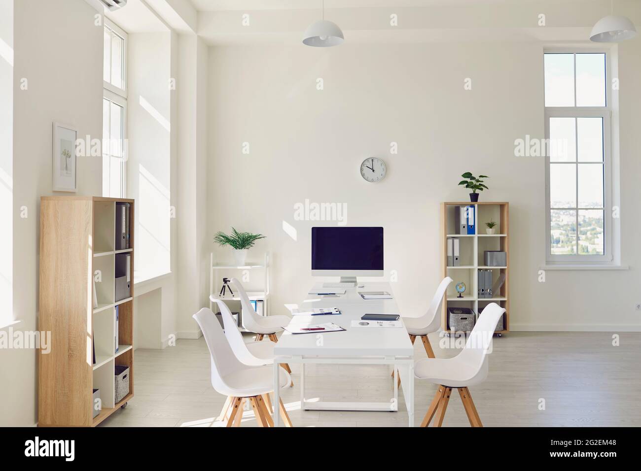 Die Inneneinrichtung des gemütlichen hellen Sitzungssaal mit großem Tisch, modernen Stühlen und einem Desktop-Computer Stockfoto