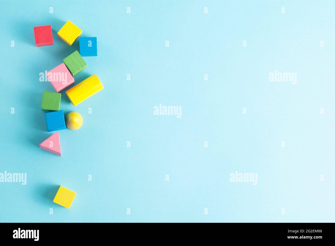 Bunte geometrische Holzfiguren auf blauem Hintergrund mit freiem Platz für Text Stockfoto