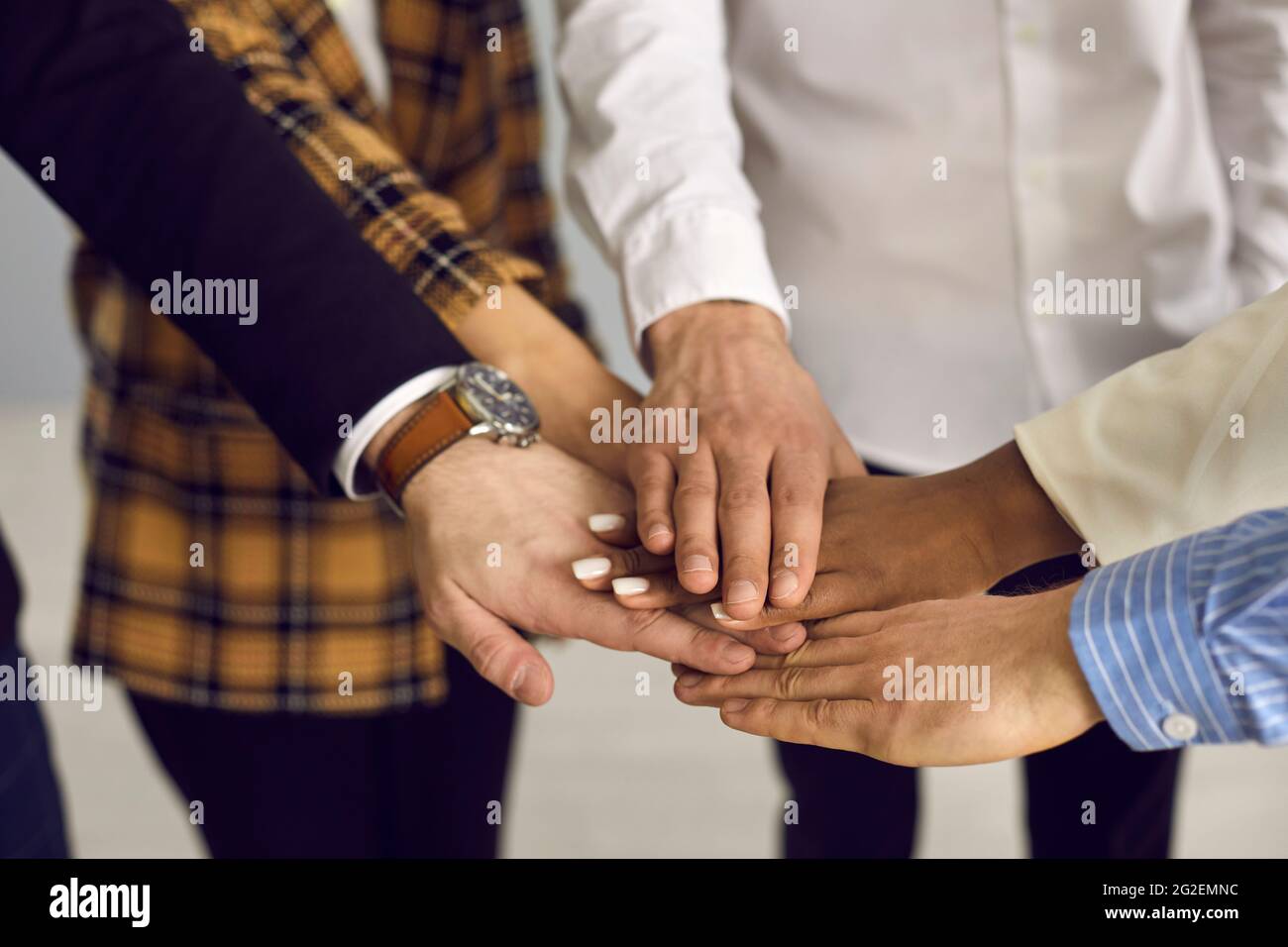 Team aus verschiedenen Geschäftsleuten, die bei einem Arbeitstreffen im Unternehmen die Hände zusammenlegen Stockfoto