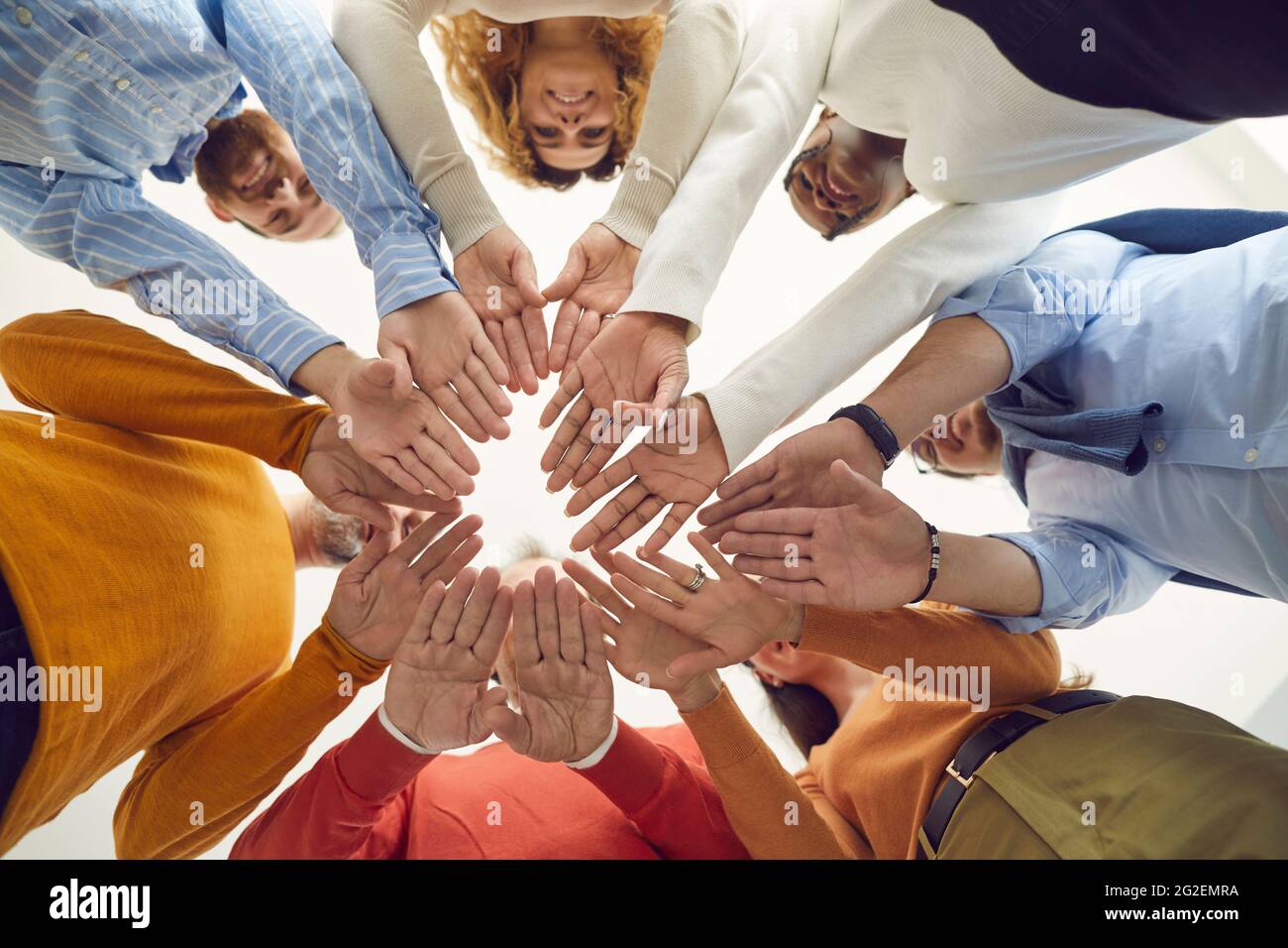 Ein Team aus positiv unterschiedlichen Männern und Frauen legt die Hände zusammen, Blick von unten Stockfoto