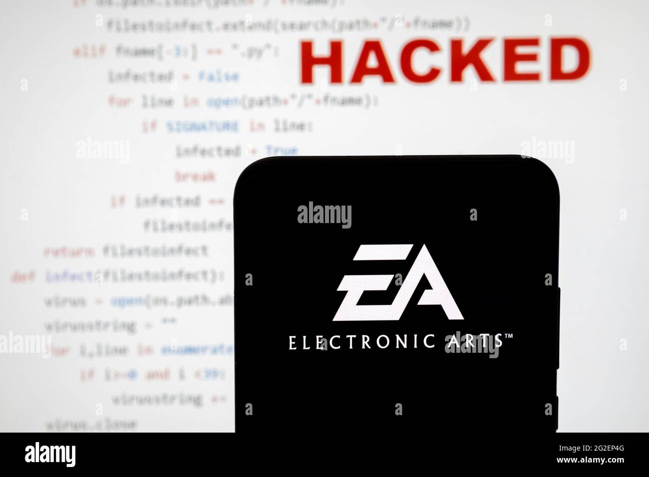 EA Electronic Arts-Logo auf einer Silhouette des Smartphones und einfacher Quellcode auf mit Wort GEHACKT auf verschwommenem Hintergrund. Konzept. ECHTES FOTO, Stockfoto