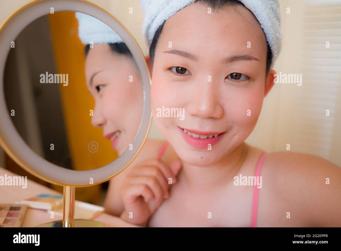 Asiatische Frau und Make-up - Lifestyle-Porträt von jungen schönen und glücklichen koreanischen Mädchen mit Handtuch Kopf Wrap neben dem Spiegel nach dem Lächeln fröhlich in Ba Stockfoto