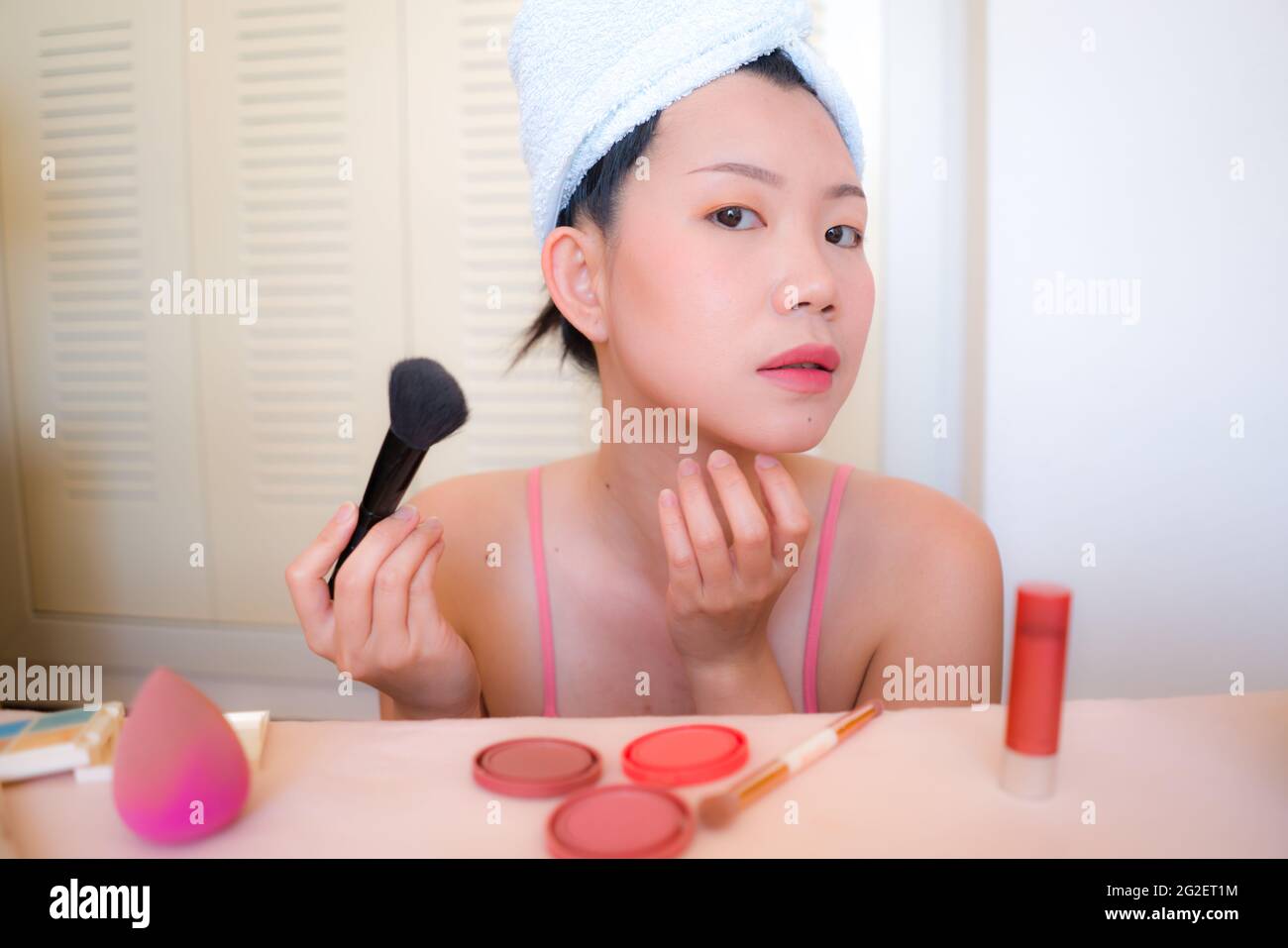 Asiatische Frau und Make-up - junge glückliche und schöne japanische  Mädchen mit Handtuch Kopf Wrap mit Pinsel Blick auf Bad Spiegel in  Schönheit und Mode konz Stockfotografie - Alamy