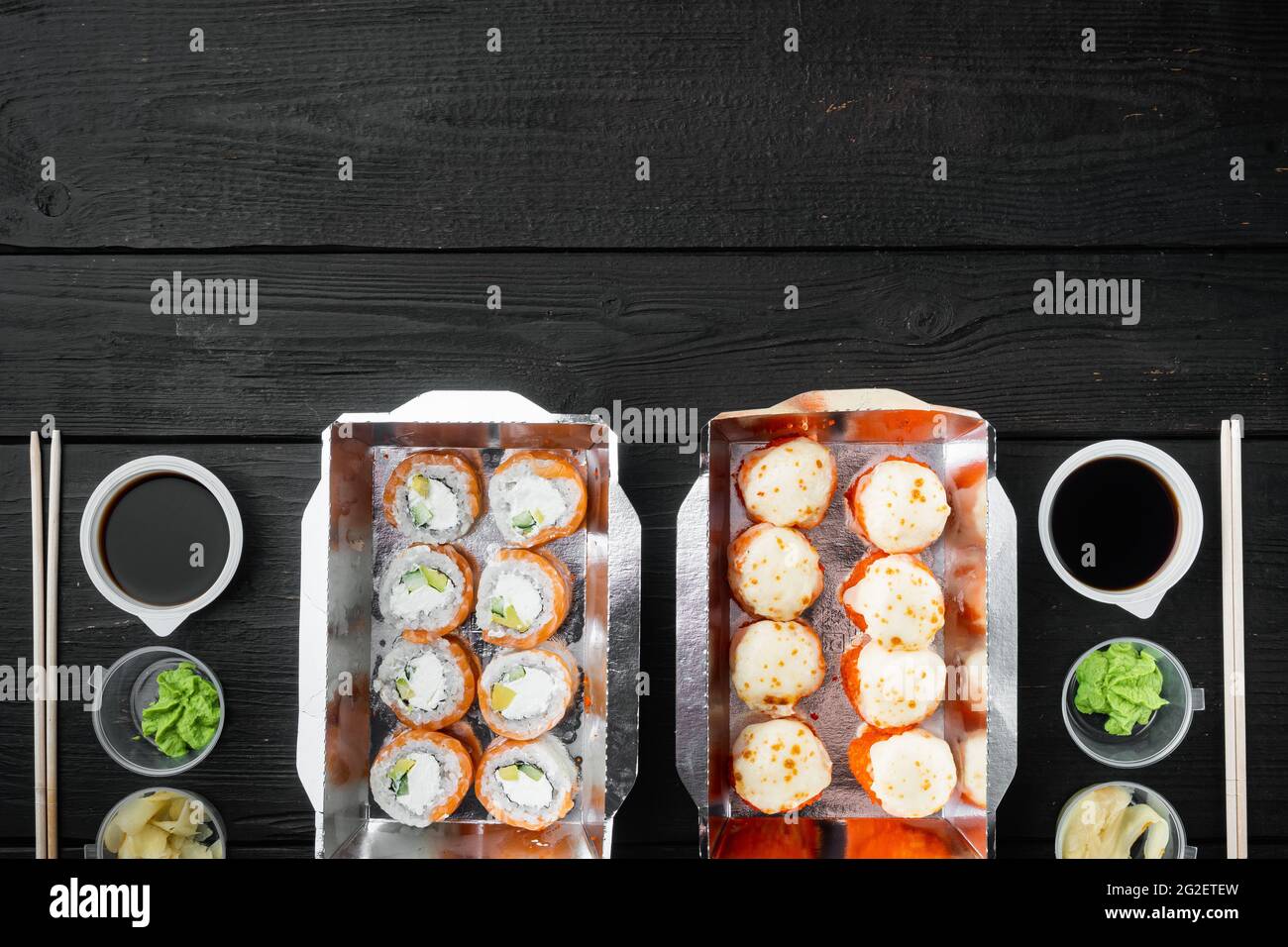 Vielfalt an verschiedenen Sushi und Rollen, Lachs und Thunfisch im Lieferlebensmittelkonzept, auf schwarzem Holztisch Hintergrund, Draufsicht flach liegend, mit Polizist Stockfoto