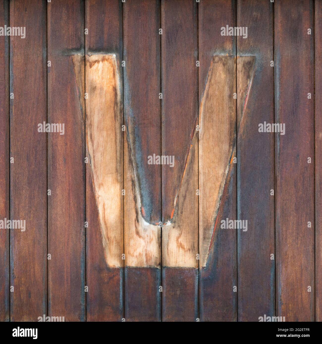 Spuren des demontierten Buchstabens V auf braunen Holzbrettern Stockfoto