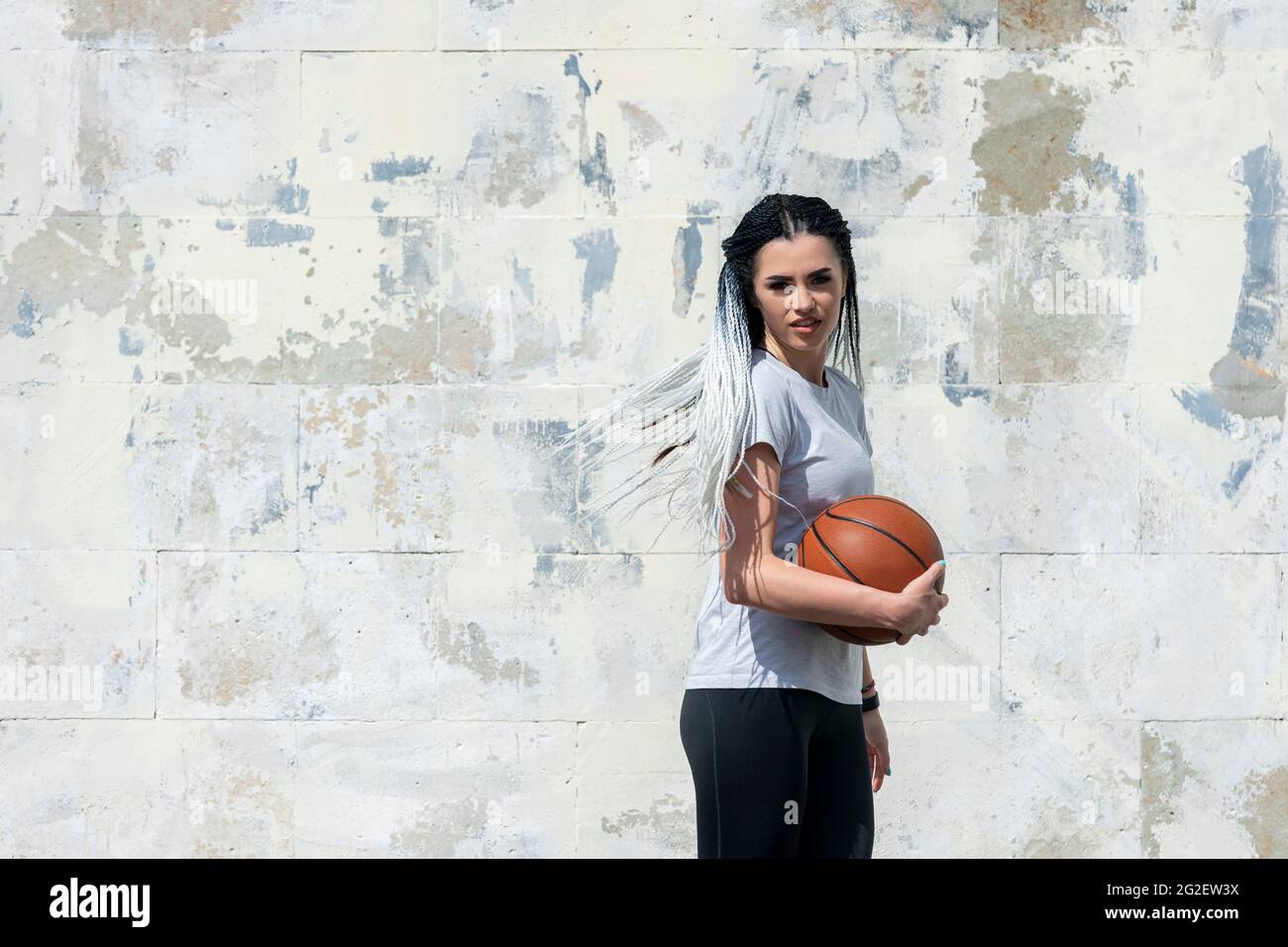 Frau mit afrikanischen Zöpfen spielt Basketball in einem Park. Jugend, Lifestyle-Konzept Stockfoto