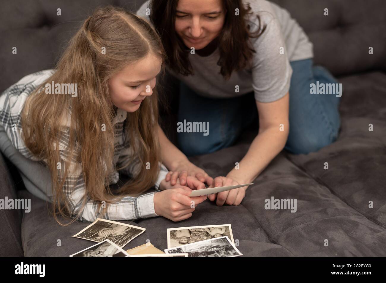 Mutter und Tochter sitzen auf dem Sofa und schauen sich ein altes Familienfotoalbum an. Stockfoto