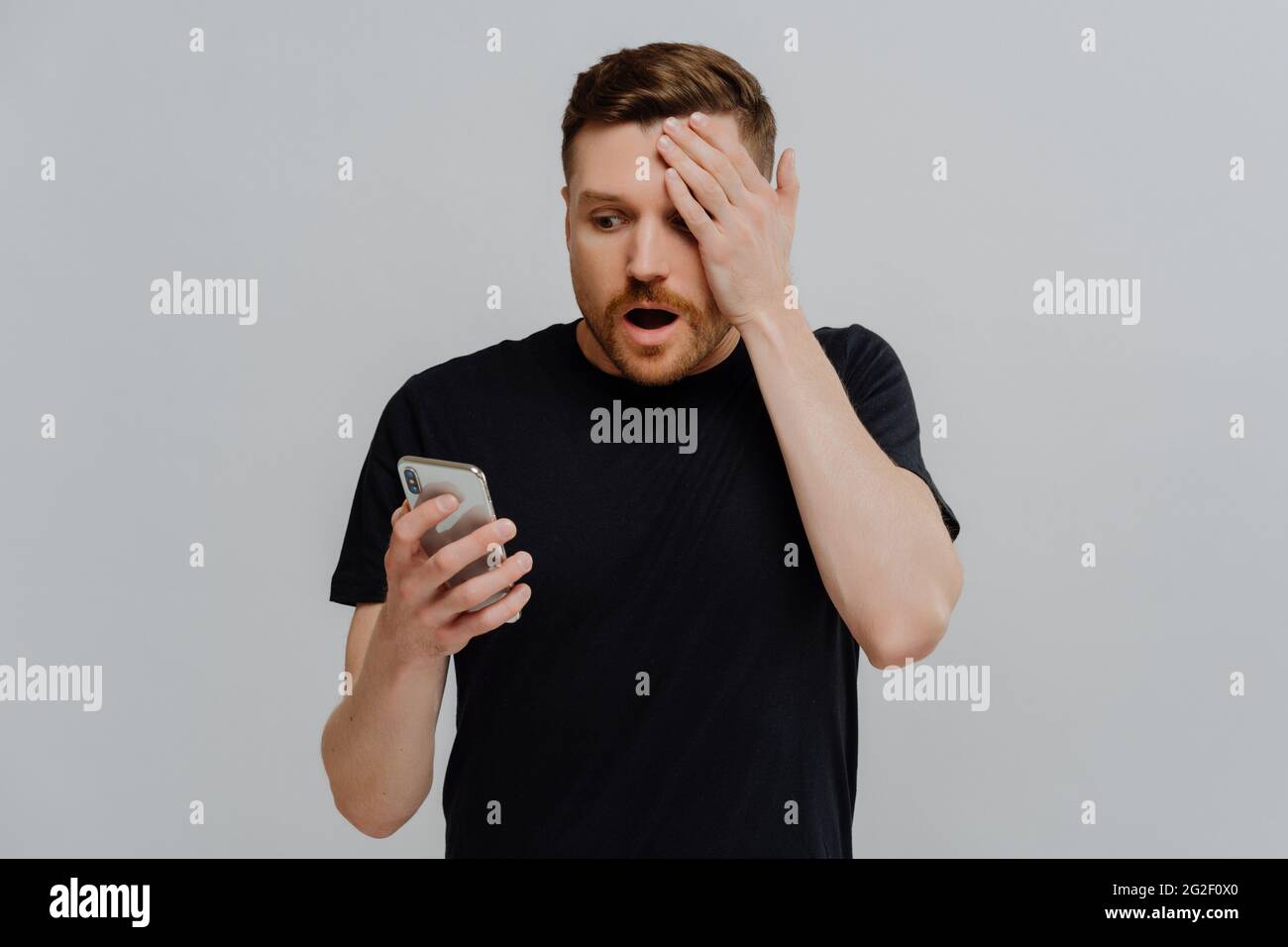 Beeindruckter Kerl, der unerwartete Nachrichten in den sozialen Medien auf dem Smartphone mit erstaunlichem Ausdruck liest Stockfoto