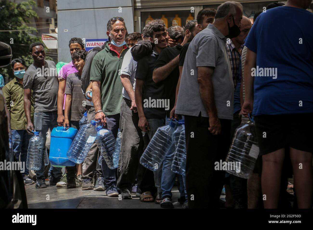 Beirut, Libanon. Juni 2021. An einer Tankstelle in Beirut warten Menschen mit Plastikgallonen in der Schlange. Der Libanon kämpft mit einem erheblichen Mangel an medizinischer Versorgung und Kraftstoff, sodass Autofahrer inmitten einer sich verschärfenden Wirtschaftskrise stundenlang an Tankstellen im ganzen Land Schlange stehen. Quelle: Marwan Naamani/dpa/Alamy Live News Stockfoto